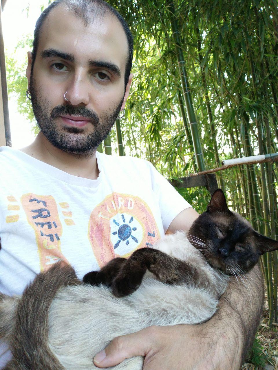 Sergio holding a male cat, Coccolone, who is being extra cuddly and slightly chonky